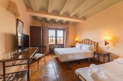 a hotel room with two beds and a television at Cigarral de Caravantes in Toledo