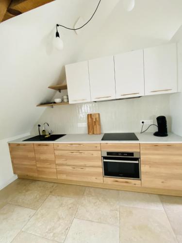 a kitchen with white cabinets and a stove top oven at Domaine de la Quenouille Appt A in Péronne