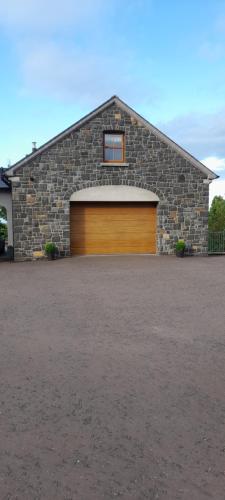 a garage with a stone building with a wooden door at Brodleys' Hill Studio 286d in Ballymena