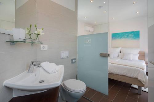 ein Badezimmer mit Waschbecken und Toilette und ein Bett in der Unterkunft Salt in Trogir