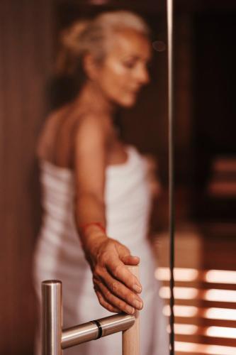 a woman in a white dress leaning on a rail at Haus Himmelfahrt in Soprabolzano