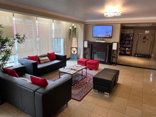 a living room with couches and a flat screen tv at The Glengate Hotel & Suites in Niagara Falls