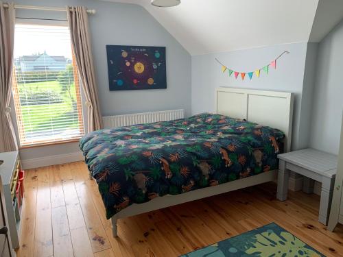 Fenit的住宿－Kerry Coastal Hideaway，一间卧室配有一张带床罩的床和窗户