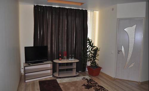 a living room with a television and a table in front of a window at Hotel Ellegance 