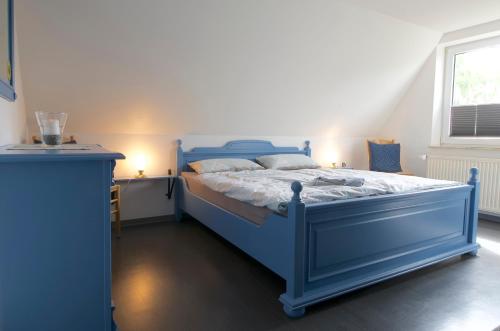 Cama azul en habitación con ventana en FeWo Birkenweg, en Schneverdingen