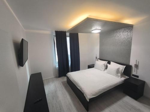 una camera da letto con letto, lenzuola e cuscini bianchi di Romana Residence a Bucarest