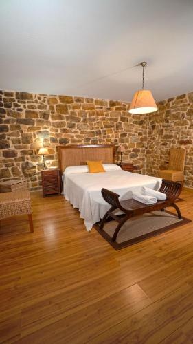 a bedroom with a bed and a stone wall at Posada Venta Hornizo in Arenas de Iguña