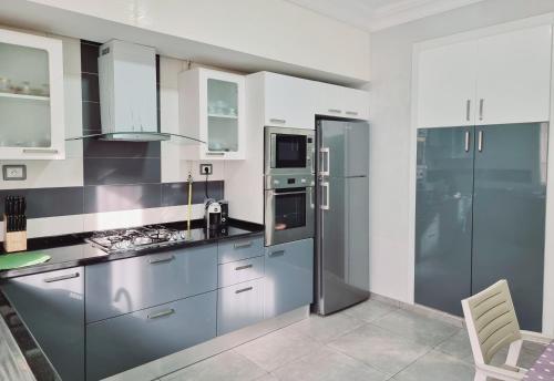uma cozinha com um frigorífico de aço inoxidável e armários em Apart haut standing v mer em Sousse