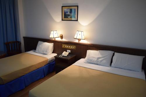 two beds in a hotel room with two lamps at Hotel Sri Garden Sdn. Bhd. in Kangar