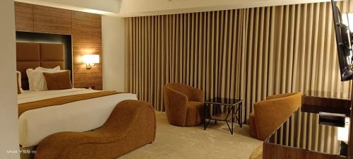 a hotel room with a bed and two chairs at فندق بلفيو بارك رويال Bellevue Park Royal Hotel in Taif