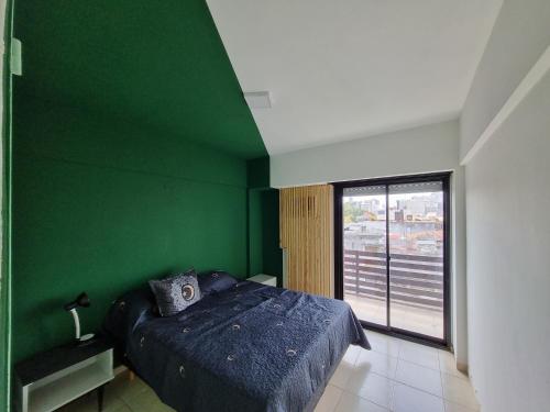 a green bedroom with a bed and a large window at Temporario 3B in Resistencia