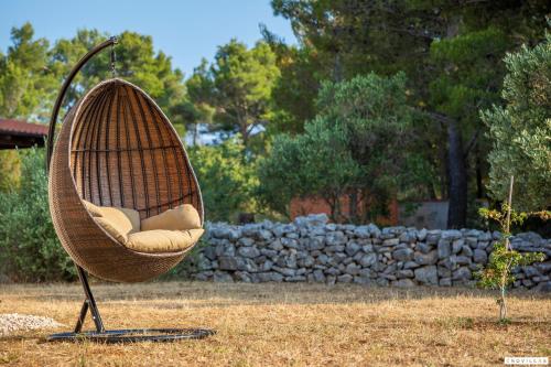 a swing chair sitting in a yard with a stone wall at Sonia Hvar in Rudina