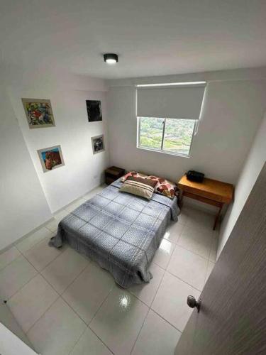 a bedroom with a bed and a table and a window at Apartamento en Bucaramanga in Bucaramanga