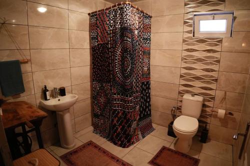 a bathroom with a shower curtain and a toilet at The Serenity House in Nar