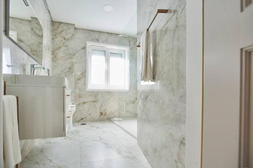 een witte badkamer met een wastafel en een raam bij Family Porto in Porto