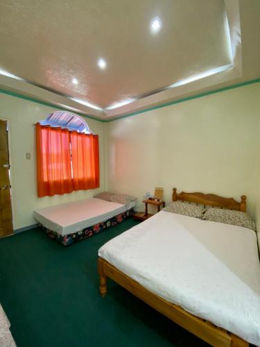 sypialnia z 2 łóżkami i oknem z czerwonymi zasłonami w obiekcie Anda Seabreeze Pension Haus w mieście Anda