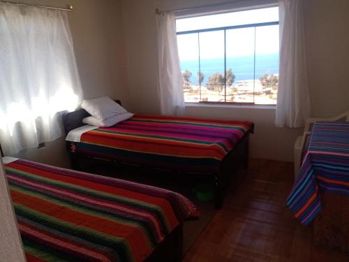- une chambre avec deux lits en face d'une fenêtre dans l'établissement Tukuypaj Amantani, à Ocosuyo