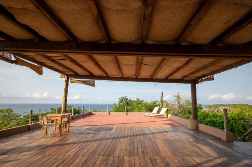 a wooden deck with chairs and a view of the ocean at Hotel Sal de Mar in San Agustinillo