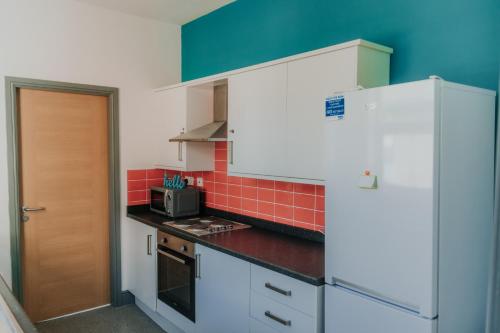 uma cozinha com armários brancos e uma parede de azulejos vermelhos em Hylton - 3 Bdrm Apt City Ctre sleeps 5 Ideal for Contractors em Pallion