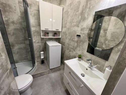 a bathroom with a sink and a toilet and a mirror at Apartamenty KoktajLOVE in Kielce