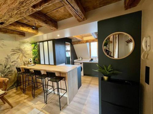 a kitchen with a bar with stools and a mirror at L'Eden du Vignoble - Centre historique de Barr in Barr