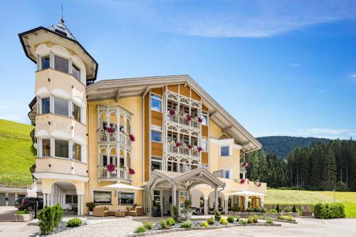 a large yellow building with flowers in front of it at Hotel Erika in Braies