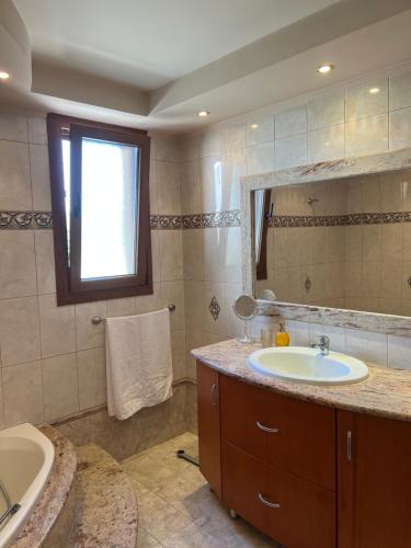 ein Badezimmer mit einem Waschbecken, einer Badewanne und einem Spiegel in der Unterkunft Luna's Summer House in Kremasti