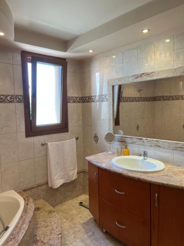 a bathroom with a sink and a tub and a mirror at Luna's Summer House in Kremasti