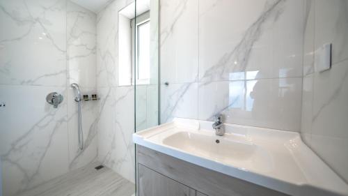 a white bathroom with a sink and a shower at Nafsika Xenia - Alkinoos Villa in Plátanos