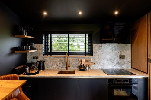 uma cozinha com um balcão com um lavatório e uma janela em The Black Cabin Oban em Oban