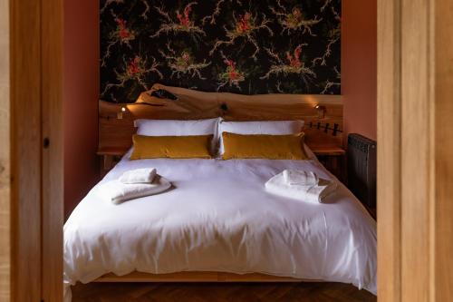 1 dormitorio con 1 cama blanca grande con almohadas amarillas en The Black Cabin Oban en Oban