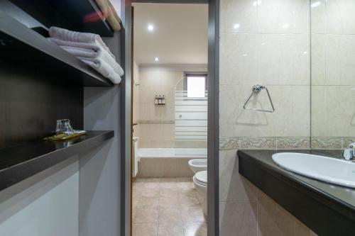 La salle de bains est pourvue d'un lavabo, de toilettes et d'une baignoire. dans l'établissement Harmonie Hotel De Montaña - Adults only, à Villa General Belgrano
