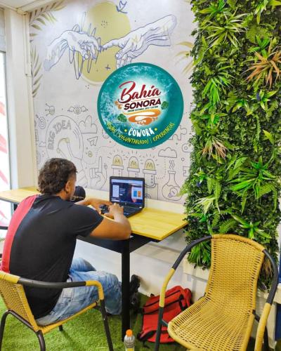 a man sitting at a table with a laptop computer at Posada Cultural Bahia Sonora in San Andrés