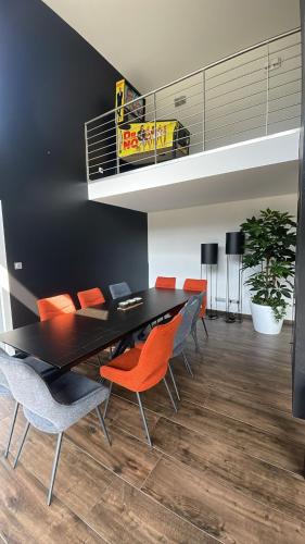 a dining room with a black table and orange chairs at Villa 4 Saisons, avec piscine chauffée et jacuzzi in Gérardmer