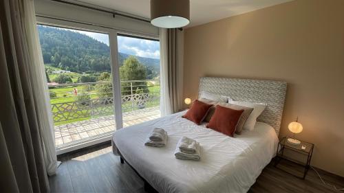 ein Schlafzimmer mit einem Bett und einem großen Fenster in der Unterkunft Villa 4 Saisons, avec piscine chauffée et jacuzzi in Gérardmer