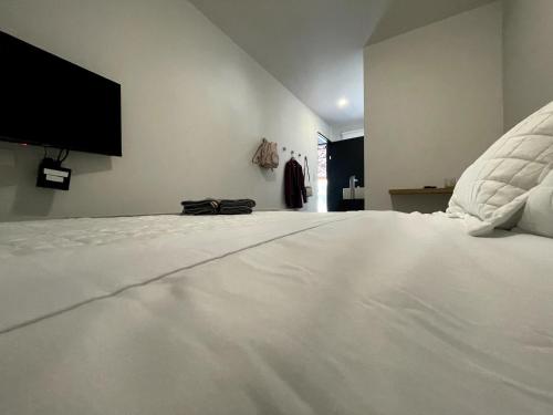 a large white bed with a flat screen tv on the wall at Nina´s - Juan Santamaria in Alajuela City