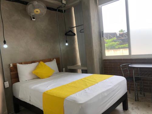 ein Schlafzimmer mit einem Bett mit einer gelben und weißen Decke in der Unterkunft Hotel RHV in Zihuatanejo