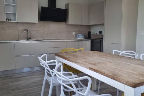 a kitchen with a wooden table and white chairs at Villetta con giardino in Genova