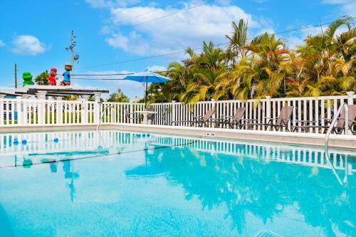 une piscine avec une clôture blanche et des palmiers dans l'établissement Cottage Near Beach, Heated Pool, Full Kitchen!, à Fort Myers