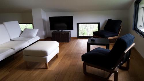 a living room with a white couch and two chairs at Apartments Lom in Most na Soči