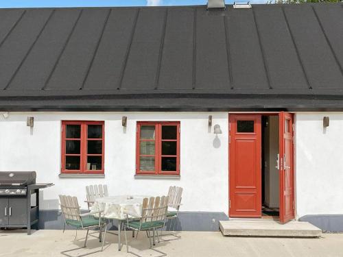 a white house with a red door and a table and chairs at 4 person holiday home in SKURUP in Skurup