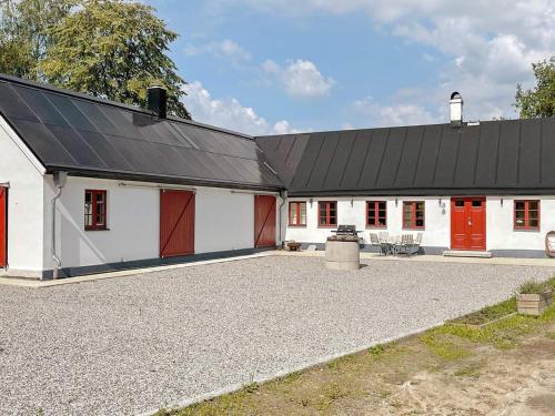 a white barn with red doors and a black roof at 4 person holiday home in SKURUP in Skurup