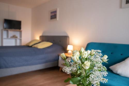 a bedroom with a blue couch and a vase of flowers at Sun Valley Apartments in Maishofen