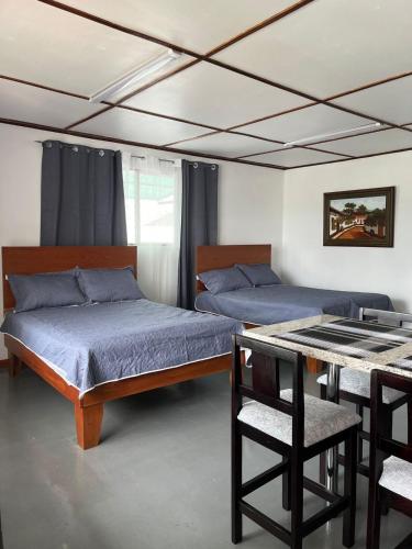 1 dormitorio con 2 camas y mesa con sillas en MARIO en Alajuela City