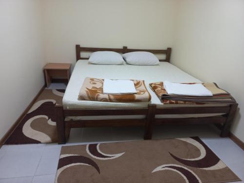 een slaapkamer met een bed met 2 kussens en een tapijt bij Apartman ALEXANDAR in Bogatić
