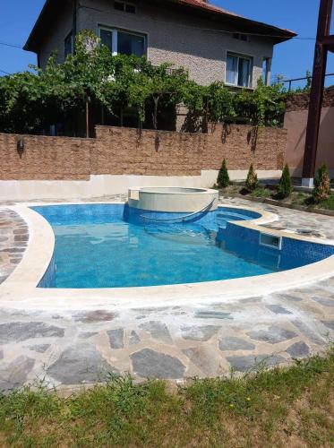 a swimming pool with blue water in front of a house at Guesthouse Gaby in Sapareva Banya