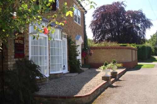 a brick house with white windows and a driveway at Pinfield Boutique Hotel in Slough