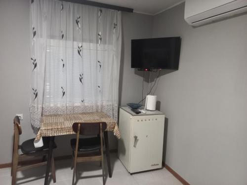 een kamer met een tafel en een televisie en een tafel en stoelen bij Apartman ALEXANDAR in Bogatić