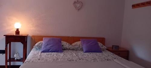a bedroom with a bed with purple pillows and a lamp at Haus Granata Family - Trekking - Bike in Giazza