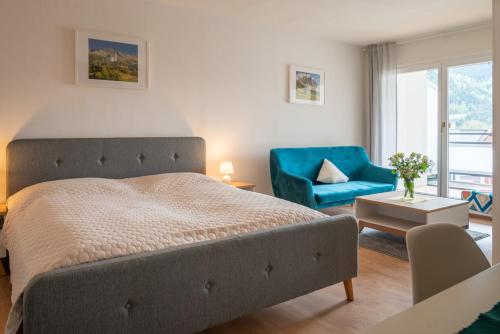 a bedroom with a bed and a blue chair at Sun Valley Apartments in Maishofen